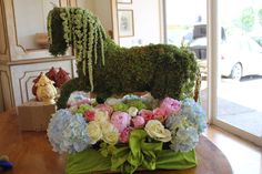 a horse made out of moss sitting on top of a table with flowers in it