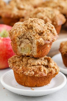 two muffins stacked on top of each other with an apple in the background