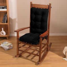 a rocking chair with black cushions in a living room next to a bookcase and dog