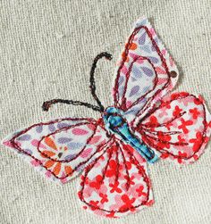 a close up of a butterfly on a piece of cloth with stitches in the middle