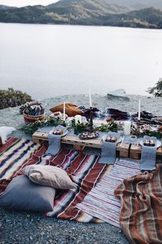 an outdoor picnic with food and candles on the ground next to it, along with other items