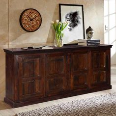 a large wooden cabinet sitting in a living room next to a wall with a clock on it