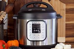 an electric pressure cooker sitting on top of a counter next to vegetables and spices