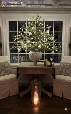 a christmas tree is lit in front of a window