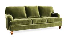 a green velvet couch with wooden legs