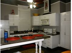 a kitchen with white cabinets and red plates on the counter