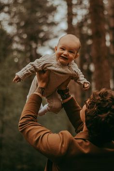 Photograph in the woods of a dad holding up their baby above their head and the baby smiling towards the camera. Family Pictures In Forest, Fall Forest Photoshoot Family, Family Photo With Newborn Outdoor, Forest Family Photoshoot Summer, Fall Family Photos Infant, Family Pictures Park, Baby Forest Photoshoot, Baby Christmas Photos Outdoor