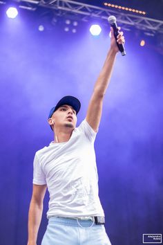 a man holding a microphone up in the air with his right arm raised to the sky