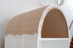 an unfinished wooden arch in the corner of a room with red carpet and white walls