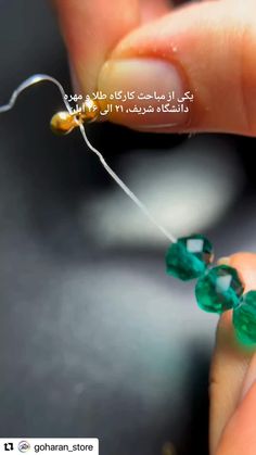 a person holding a string with green beads on it and an arabic text above the string