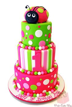 a three tiered cake decorated with pink, green and white stripes and a ladybug on top