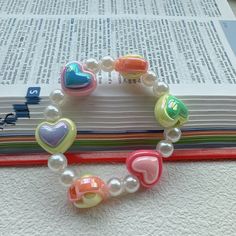 a bracelet made out of plastic beads and heart charms on top of an open book