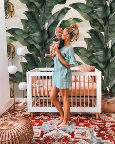 a woman is holding a baby in her arms while standing next to a wall mural