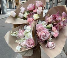 a woman is holding several bouquets of flowers on the street in front of a building