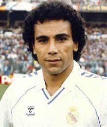 a man standing in front of a crowd wearing a white uniform and holding a soccer ball