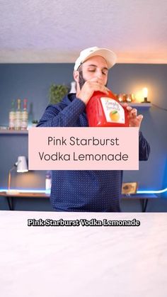 a man in a hat is holding a bottle of pink starburst vodka lemonade