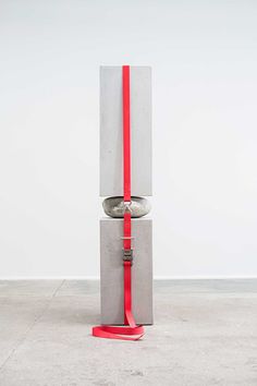 a sculpture with a red ribbon around it's neck on concrete blocks in an empty room