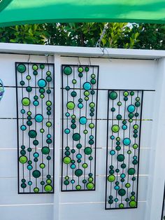 two metal panels with green and blue circles on them, hanging from a white wall