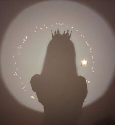 the silhouette of a woman with a crown on her head in front of a foggy background