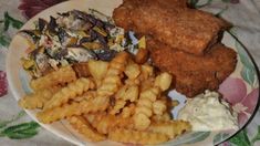 fried chicken, fries and coleslaw are served on a floral - print plate