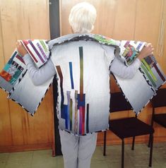 a person standing in front of a wooden wall holding up several pieces of paper and magazines