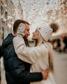 a man and woman standing next to each other in front of a string of lights