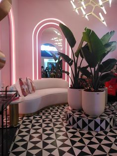 a living room with black and white flooring and large potted plants in the corner