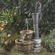 an outdoor water fountain with two wooden barrels and a faucet in the middle