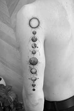 a man's back with the solar system tattoo on his arm