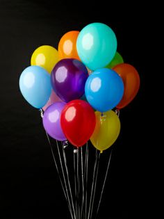 a bunch of balloons that are in some kind of cup on a table with black background