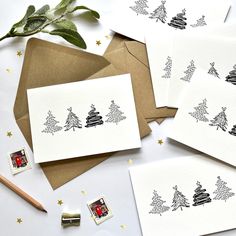 four christmas cards with stamps on them next to a pencil and some paper work supplies