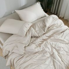 an unmade bed with white sheets and pillows