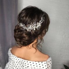 a woman wearing a white polka dot dress with a hair comb on her head and flowers in her hair