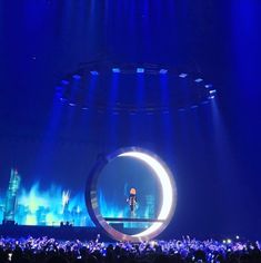 a person standing on top of a stage in front of a large circular light fixture