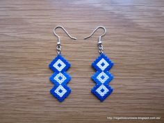 a pair of blue and white beaded earrings sitting on top of a wooden table