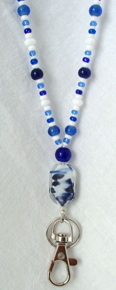 Blue & White Beaded Lanyard This Blue & White Beaded Lanyard can be used as a badge holder, an I.D. holder, keychain necklace, watch holder - it's a multi-use accessory for home or office! 34" in length, long enough to put on or remove overhead. It also has an easy-to-use metal lobster clasp for your convenience. It's made with blue and white glass beads and strung on strong C-Lon beading cord. Snap-on badge holder, clip, and keyring are included to keep your badges or keys ready when you need t Adjustable Beaded Blue Lanyards, Adjustable Blue Beaded Lanyards, Handmade Blue Lanyards For Gifts, Handmade Blue Lanyards As Gifts, Handmade Blue Lanyard As Gift, Keychain Necklace, Beading Cord, Beaded Lanyard, Watch Holder