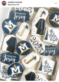 cookies decorated with royal blue and white icing are arranged in a box to look like graduation decorations