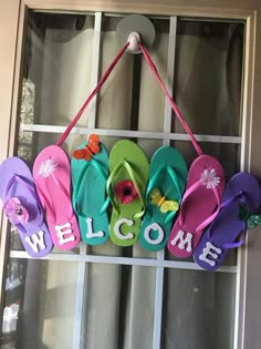 a welcome sign hanging on the side of a door with flip flops in it