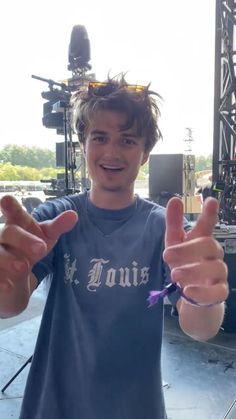 a young man giving the thumbs up sign at a music festival in front of a stage