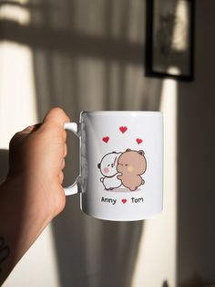 a person holding up a coffee mug with an image of a teddy bear on it