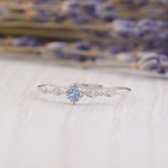 a blue and white diamond ring sitting on top of a table next to lavender flowers