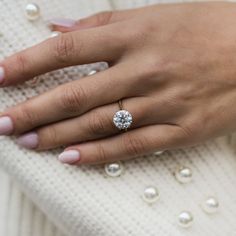 a woman's hand with a diamond ring on her finger and pearls around it