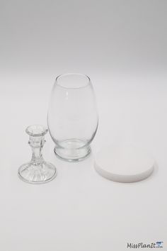 there is a glass and a candle holder next to each other on a white surface