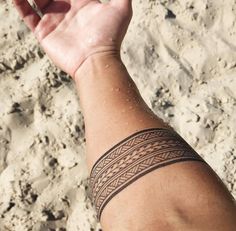 a person's arm with a tattoo on it and sand in the back ground