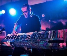 a man is playing an electronic keyboard on stage