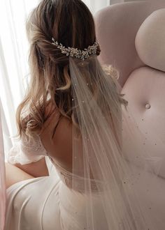 a woman wearing a wedding veil sitting on a couch