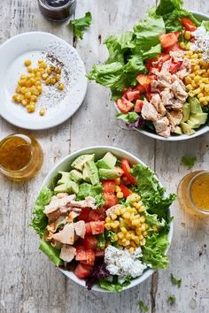 two bowls filled with salad and dressing on top of a wooden table next to drinks