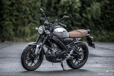 a motorcycle parked on the side of a road next to some grass and trees in the background