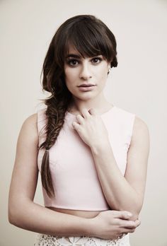 a woman with long hair wearing a pink top and braid in her hair, posing for the camera