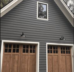 a gray house with two brown garage doors and the words kendal charcoal by benjamin moore